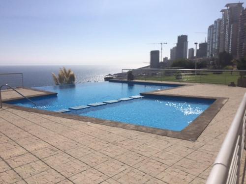 a large swimming pool with blue water in a city at Apartamento Eluchans Reñaca in Viña del Mar