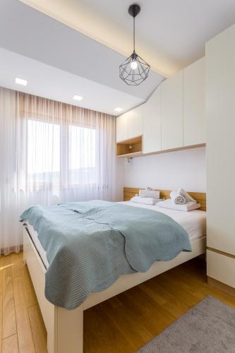 a bedroom with a large bed with a blue blanket at Delights Apartment Zlatibor in Zlatibor
