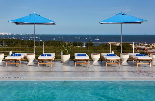 a swimming pool with lounge chairs and umbrellas on a roof at Mr. C Miami - Coconut Grove in Miami