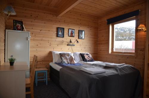 a bedroom with a bed in a wooden room at Aurora exotic cabin in Vannareid