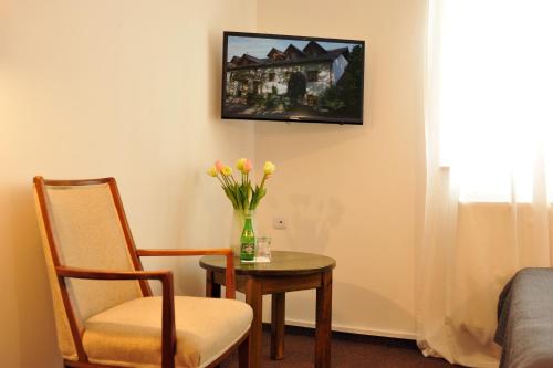 a room with a table and a chair and a vase of flowers at Hotel Protea Bolesławiec in Bolesławiec