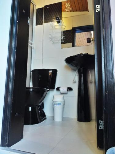 a bathroom with a black toilet and a sink at Hotel Hortensia Real in Paipa