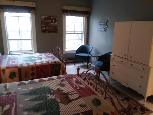 a bedroom with a bed and a dresser and two windows at The Inn in Westport in Westport