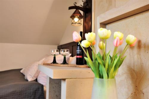 a vase filled with pink and yellow flowers next to wine glasses at Hotel Protea Bolesławiec in Bolesławiec