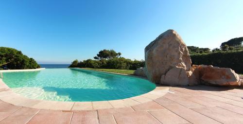 a swimming pool with a rock next to the ocean at Hotel Punta Negra in Alghero