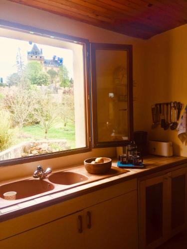 d'un évier de cuisine et d'une fenêtre avec vue sur le château. dans l'établissement Maison de Montfort, à Vitrac