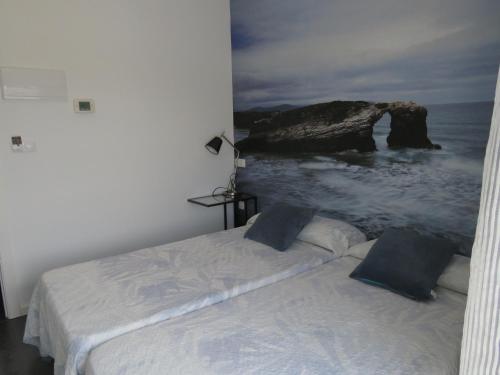 a bedroom with a bed with a rock in the ocean at Refugio O Castro in Barreiros