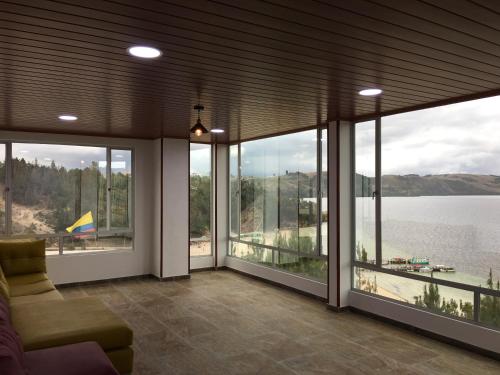 sala de estar con ventanas grandes y vistas al lago en El Arca de Noah en Tota