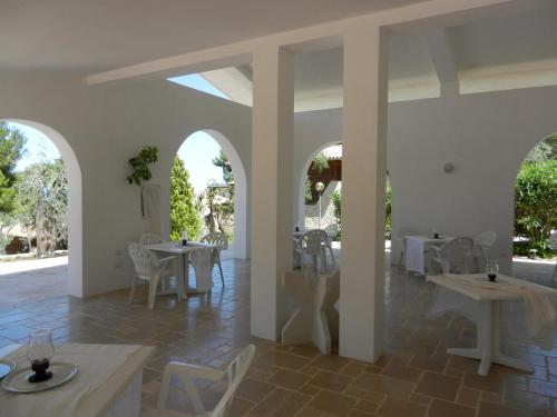 uma sala de jantar com mesas brancas e cadeiras brancas em Tenuta Molino di Mare em Rodi Garganico