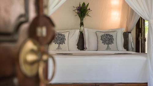 a bed with white pillows and a vase of flowers on it at Pondok Santi Estate in Gili Trawangan