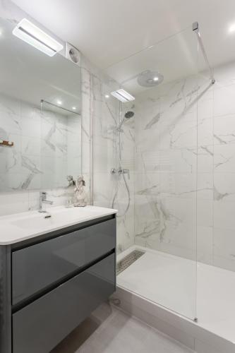 une salle de bain blanche avec une douche et un lavabo dans l'établissement Résidence Saint-Sabin, à Paris