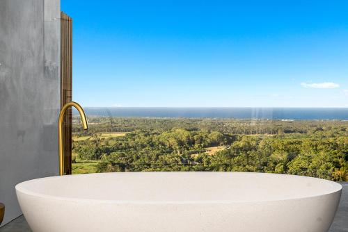 a bath tub in a bathroom with a view at Sundays at Byron in Hayters Hill