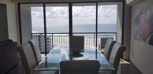 einen Esstisch mit Stühlen und Meerblick in der Unterkunft Royal Palm Resort on the Beach in Gold Coast