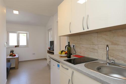 kuchnia z białymi szafkami i zlewem w obiekcie Apartments Maric-Hlapa w mieście Soline