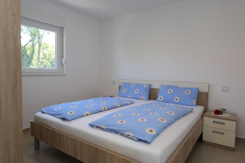 1 dormitorio con cama con sábanas azules y ventana en Apartments Maric-Hlapa, en Soline