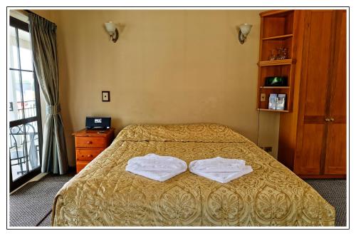 a bedroom with a bed with two towels on it at Lantern Court Motel in Reefton