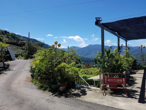 a dirt road with plants and a building with mountains in the background at Ming Yang B&B in Fenchihu