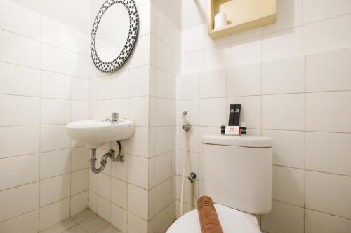 a white bathroom with a toilet and a sink at Homey and Simply 2BR Kebagusan City Apartment By Travelio in Jakarta