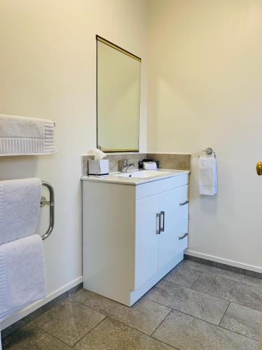 a bathroom with a white sink and a mirror at Kingswood Manor Motel in Whangarei