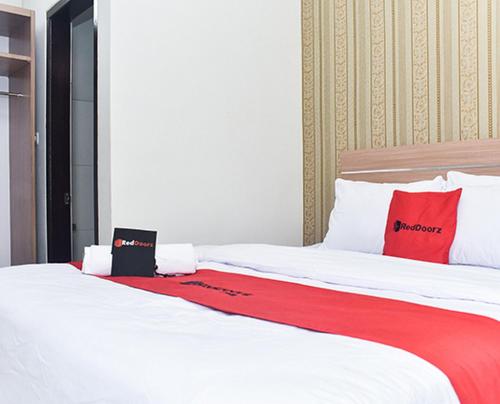 1 dormitorio con 1 cama con almohadas rojas y blancas en RedDoorz Plus near Malang Town Square, en Malang