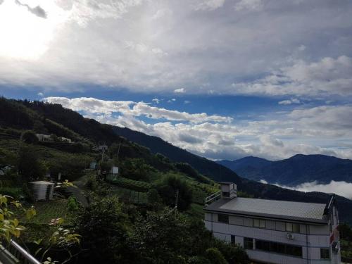 a building on a hill with mountains in the background at Ming Yang B&B in Fenchihu