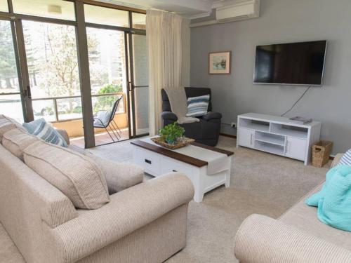 a living room with two couches and a flat screen tv at Taranaki Beach House in Port Macquarie