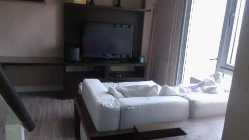 a living room with a white couch and a tv at Avida San Lazaro 1 BEDROOM with balcony near SM San Lazaro in Manila