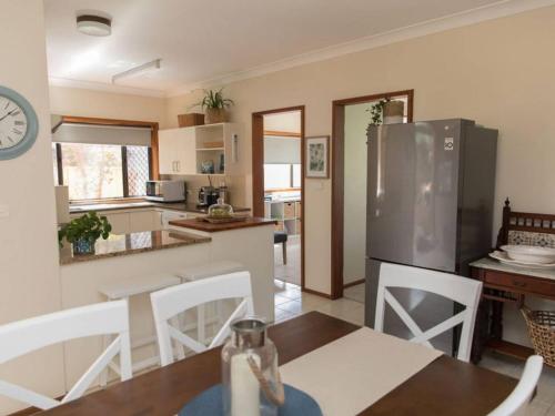 a kitchen with a dining table and a refrigerator at Taranaki Beach House in Port Macquarie