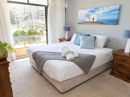 a bedroom with a large bed and a large window at Taranaki Beach House in Port Macquarie