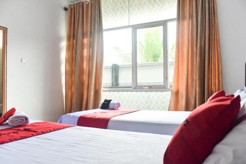 a hotel room with two beds and a window at RedDoorz near Sultan Hasanuddin Airport 2 in Makassar