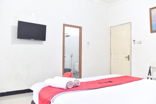 a bedroom with a bed with towels and a mirror at RedDoorz near Sultan Hasanuddin Airport 2 Makassar in Makassar