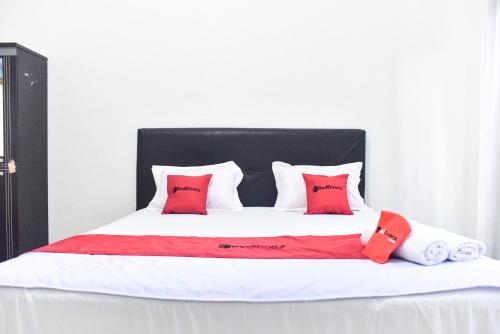 a large bed with red and white pillows on it at RedDoorz near Sultan Hasanuddin Airport 2 Makassar in Makassar