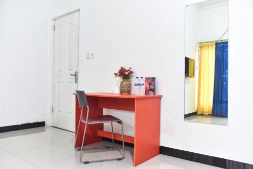 a red table with a chair and a mirror at RedDoorz near Sultan Hasanuddin Airport 2 Makassar in Makassar