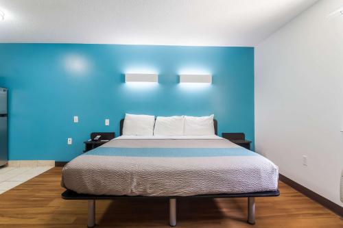 a bed in a room with a blue wall at Motel 6-Gulf Shores, AL in Gulf Shores