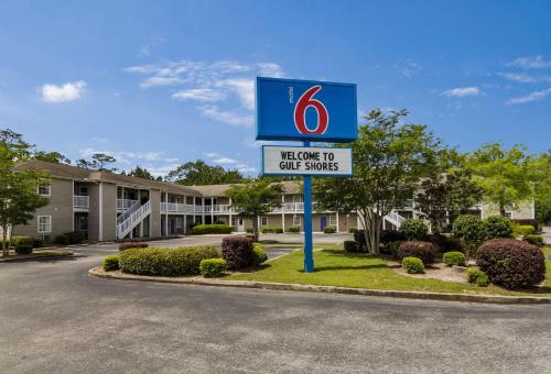 a welcome to golf shuttle sign in front of a building at Motel 6-Gulf Shores, AL in Gulf Shores