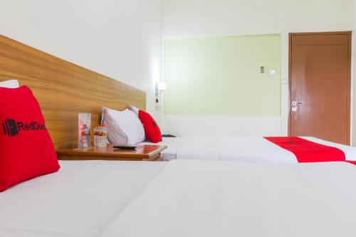 a hotel room with two beds with red pillows at RedDoorz Plus @ Surapati 2 in Bandung