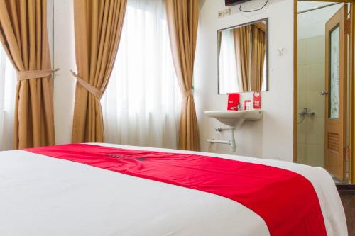 a bedroom with a red and white bed and a sink at RedDoorz Plus @ Surapati 2 in Bandung