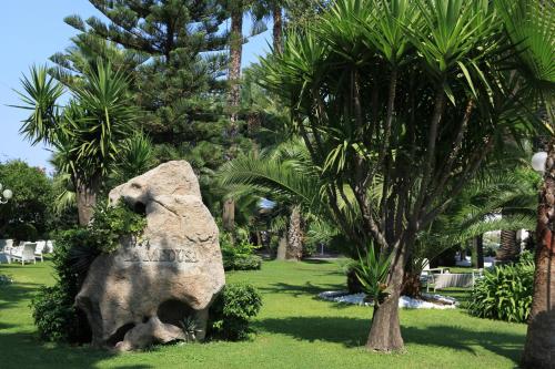 a large rock in a park with palm trees at La Medusa Hotel - Dimora di Charme in Castellammare di Stabia