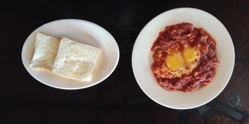 two plates of food with eggs and bread on a table at Anda Poseidon’s Beach Resort in Anda