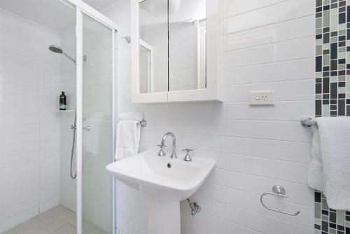 a white bathroom with a sink and a shower at Seabreeze 4 on Lawson Street in Byron Bay