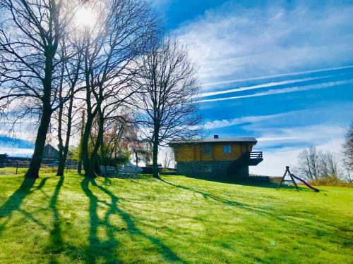 a playground in a field with trees and a building at Chalet de Charme in Rochehaut