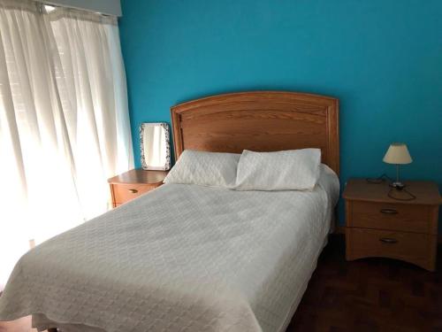 1 dormitorio con 1 cama grande y pared azul en Encantador departamento en el centro de la ciudad en Bahía Blanca