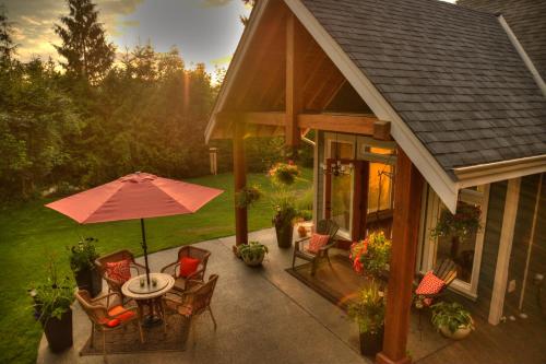 a patio with a table and chairs and an umbrella at Shawnigan Suite B & B in Shawnigan Lake