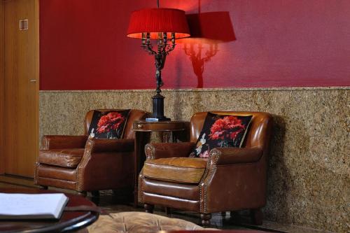 two leather chairs and a lamp in a room at Hotel Domstern in Cologne