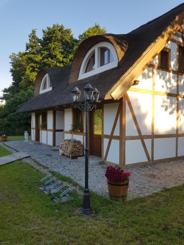 a house with a thatched roof and a light pole at Chata Pod Strzechą in Lipusz