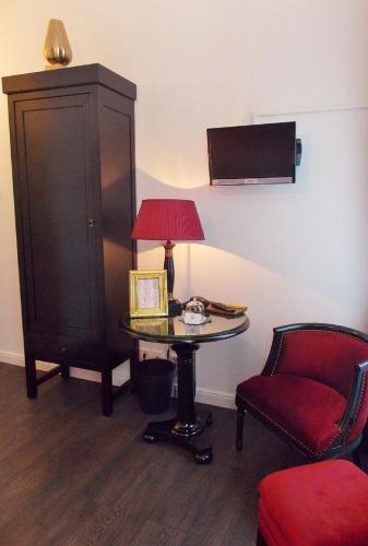 a room with a table with a lamp and a chair at Hotel Domstern in Cologne