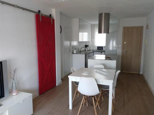 cocina con puerta roja, mesa blanca y sillas en Apartamento ENSUEñO en Cullera playa San Antonio en Cullera