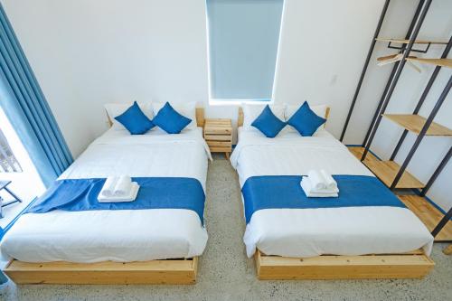 two beds in a room with blue and white pillows at SANTORI Hoi An Homestay in Hoi An