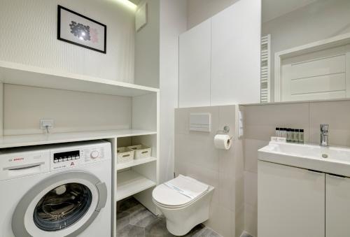 a white bathroom with a washing machine and a sink at Dom & House - Apartments Nadmorze Estate in Gdańsk