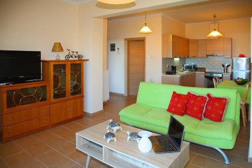 a living room with a green couch and a laptop on a table at Comfy flat with Garden near the Beach in Theológos